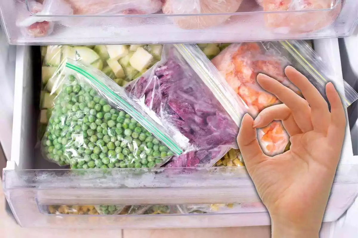 Congelador abierto con distintos tipos de verduras y una mano simulando el gesto de aprobación